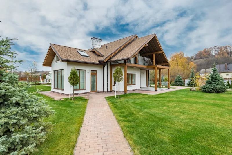 Wohnhaus mit überdachter Terrasse auf Holzstützen und angrenzendem Rasen